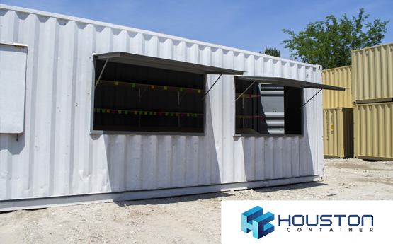 A white container home with windows and awnings.