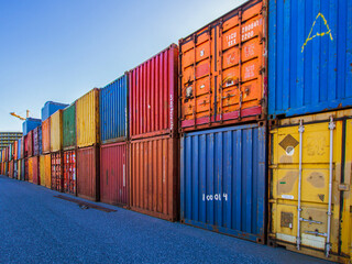 A vibrant lineup uses of storage & shipping containers neatly arranged in a parking lot, showcasing their diverse uses and colorful exteriors