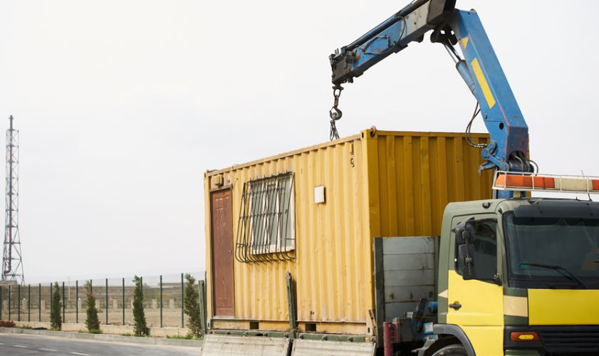 A crane is lifting a container onto the side of a building.