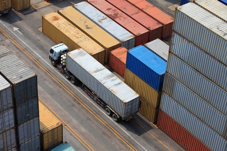  Aerial view of a truck navigating through a container yard, showcasing the vital role of containerization in the shipping industry.