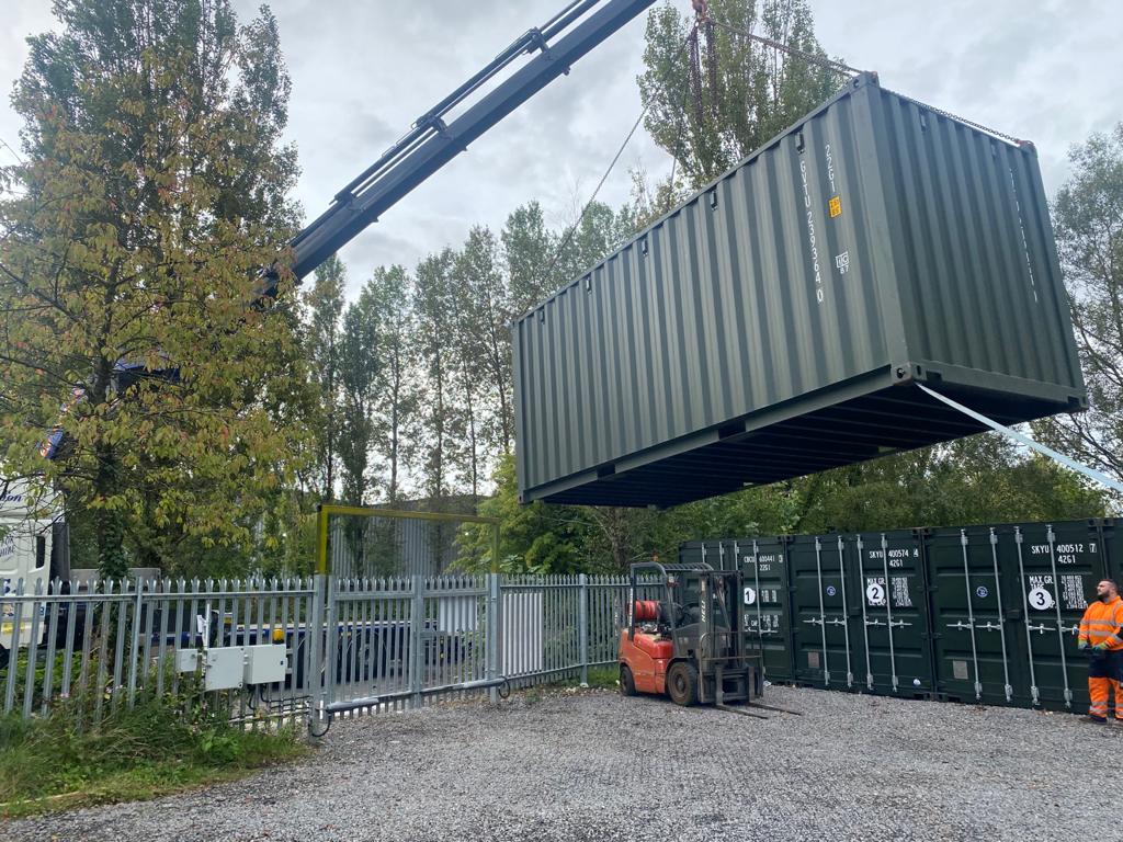 A forklift hoists a shipping container into a yard, showcasing efficient container delivery services