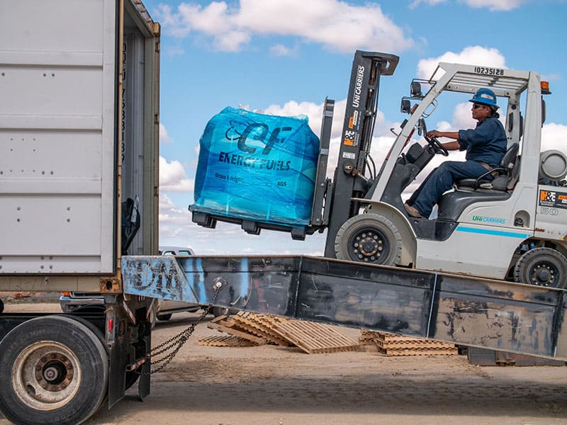  A shipping container delivery service loads a forklift with a large blue bag for transportation