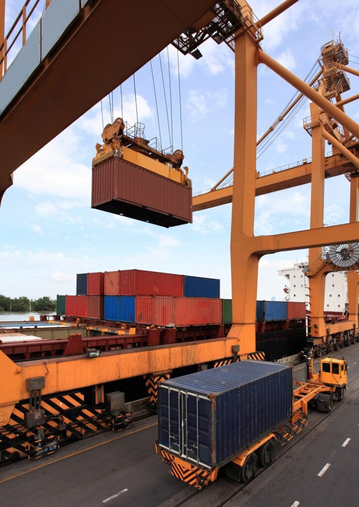A massive crane hoists a shipping container onto a truck, showcasing efficient shipping container maintenance.