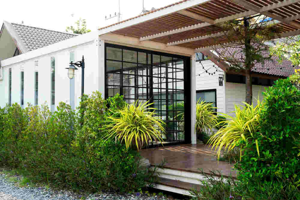 A charming house with a wooden deck and fence, serving as a shipping container home office.
