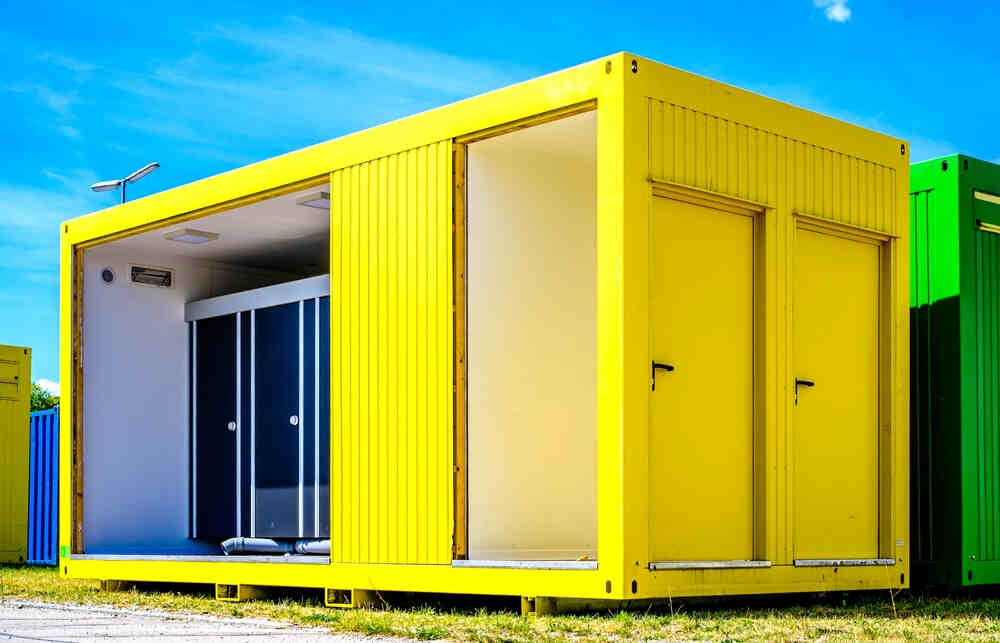Shipping container home office with open door in yellow and green.