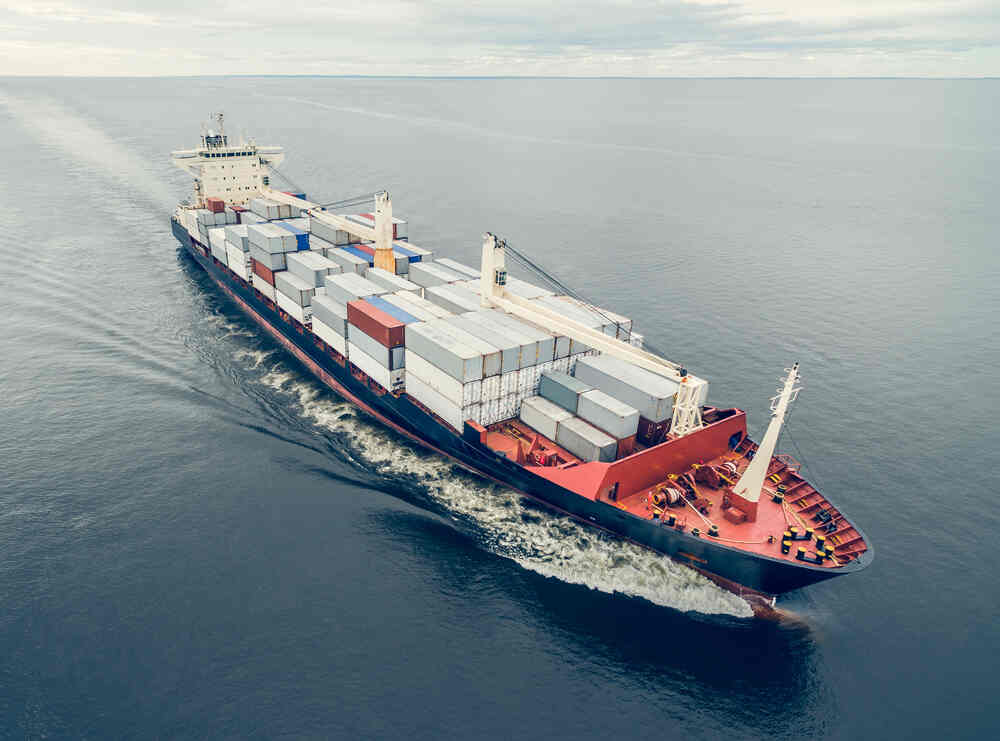 Container ship sailing on ocean with side opening shipping containers.